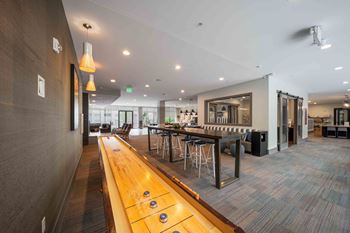 A long wooden table with several stools is in the middle of a room at Regatta Sloans Lake Apartments, Denver, Colorado